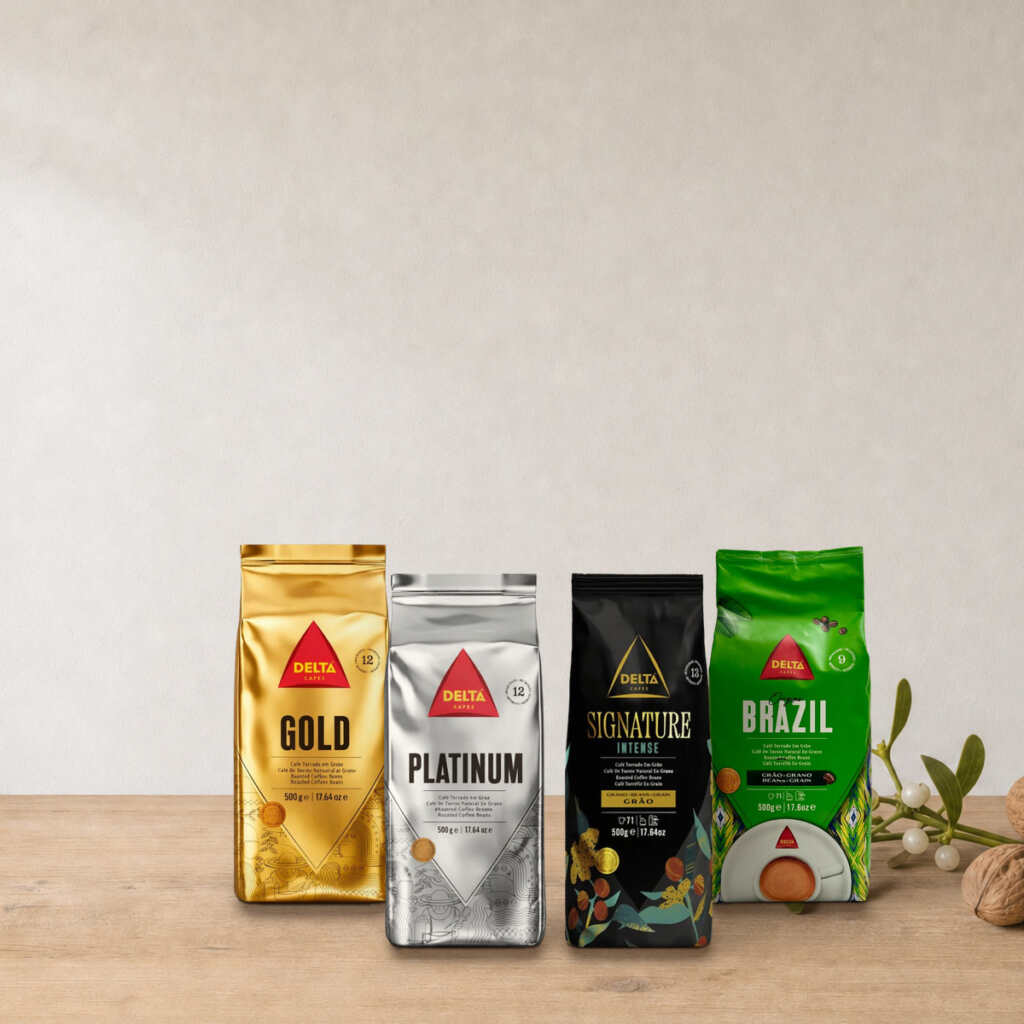 Coffret Portugal Delta Cafés sur une table en bois, près d’une branche de gui et de noix