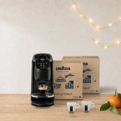 Coffret machine + cafés Lavazza Blue Classy Soul sur une table en bois, près d’une guirlande lumineuse et de clémentines