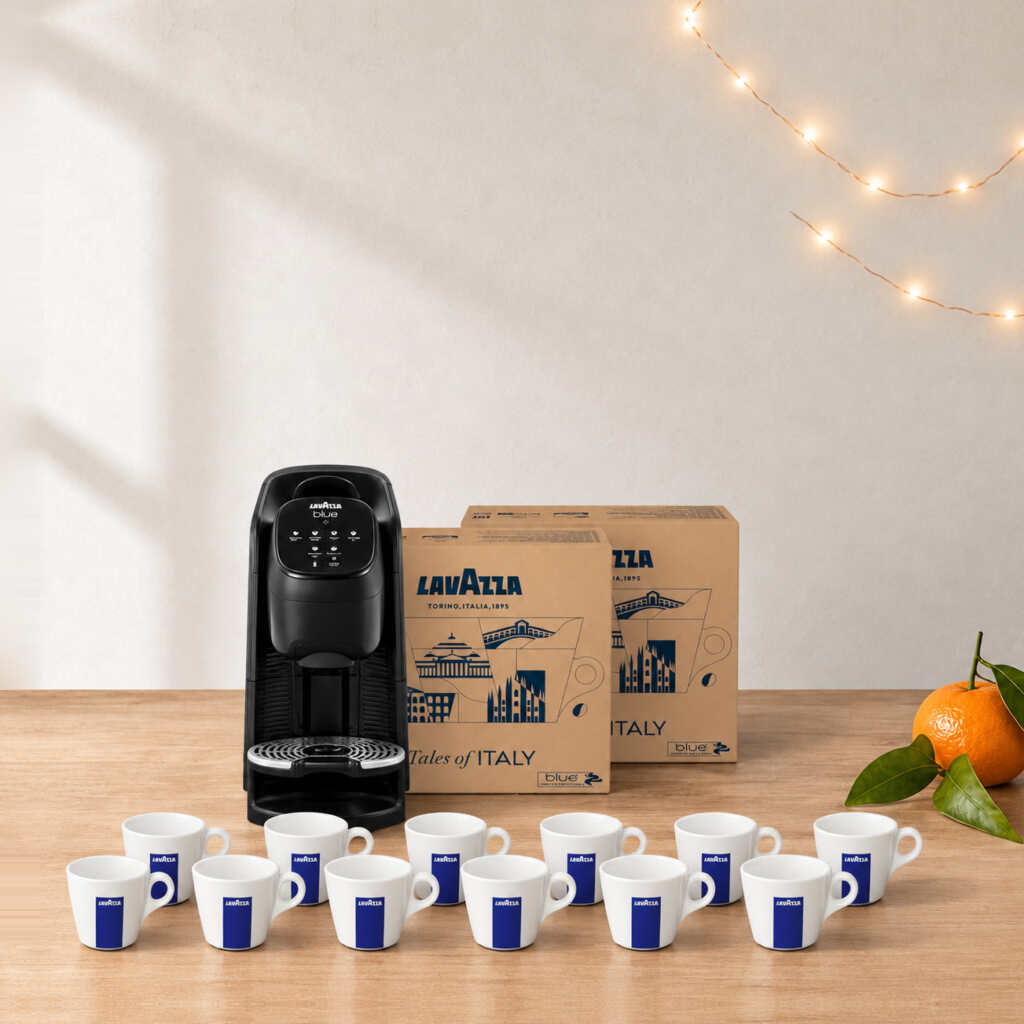 Coffret machine + cafés Lavazza Blue Classy Soul sur une table en bois, près d’une guirlande lumineuse et d’une clémentine