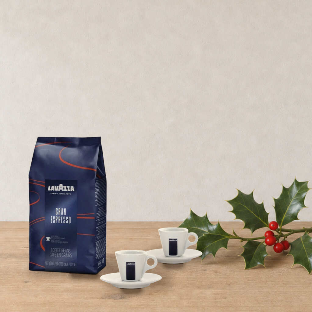 Set Espresso Lavazza sur une table en bois, près d’une branche de houx