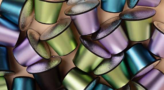 Abstract background of espresso coffee capsules of different colors and flavors.