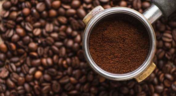 top view of ground coffee in portafilter on coffee beans background